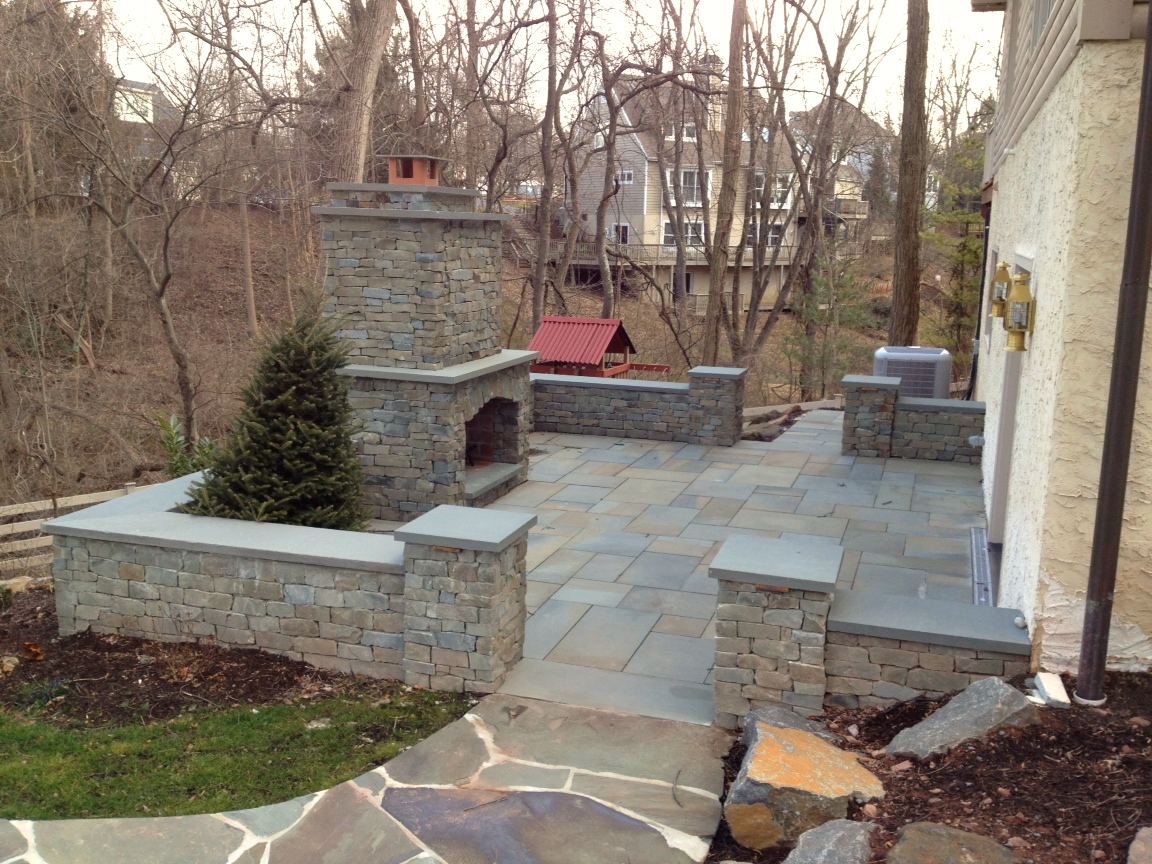 Outdoor stone fireplace with bluestone patio and sitting walls