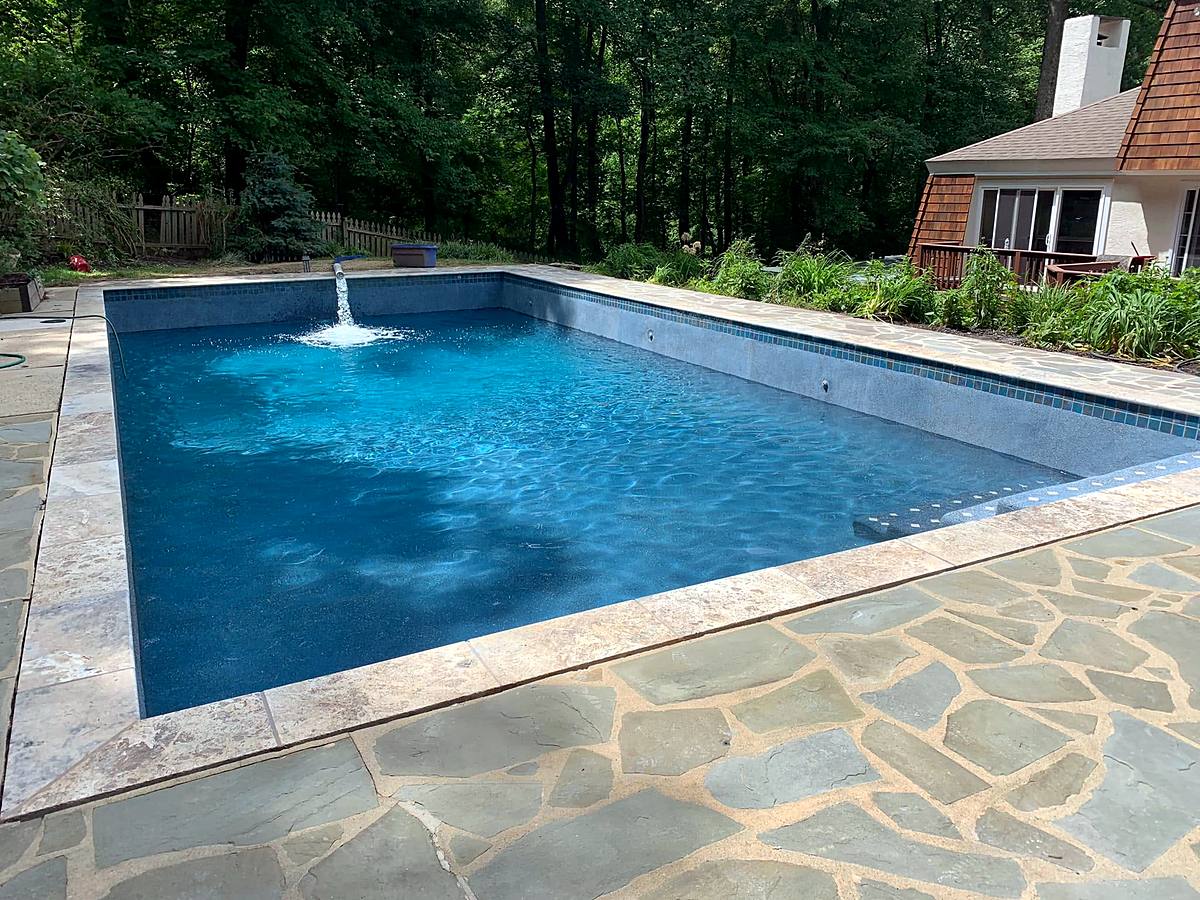 Rectangular pool with a deck jet fountain and an irregular flagstone patio