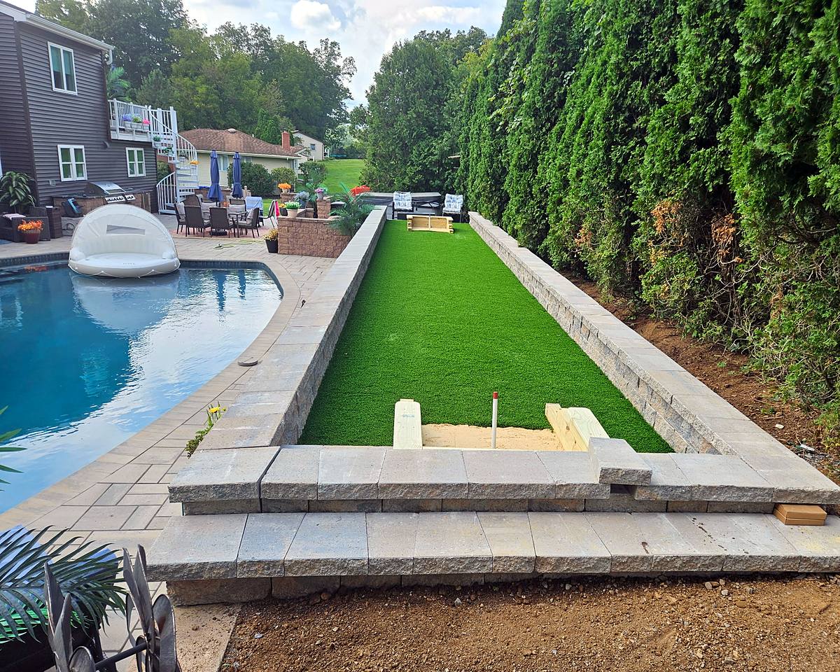 Turf horseshoe lane between new block retaining walls beside the pool, pits still being set