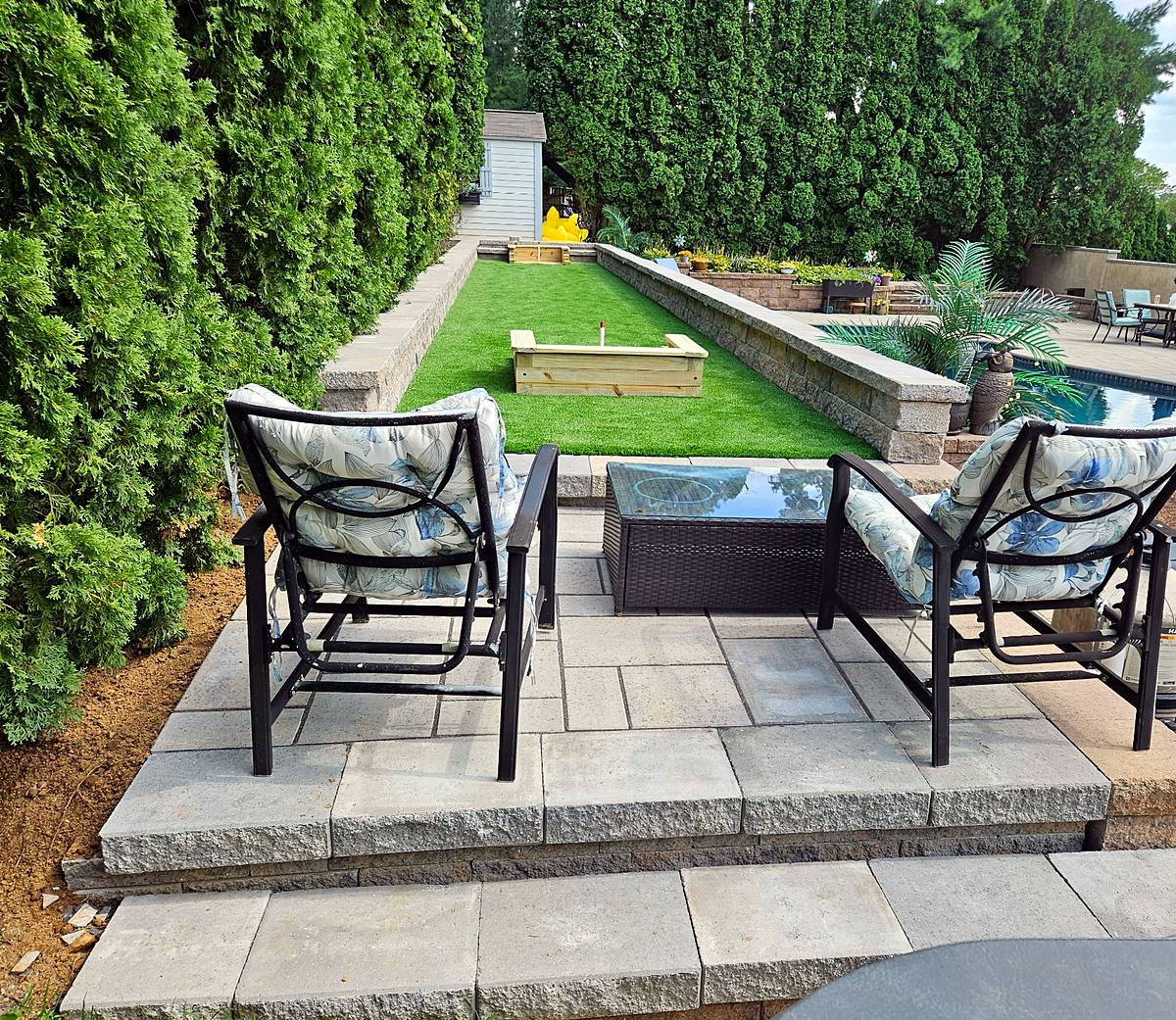 Raised paver seating patio with block steps overlooking the horseshoe lane and pool