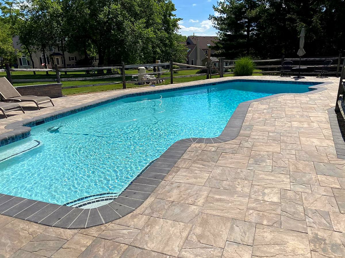 Renovated pool with new waterline tile, dark coping and a wide paver deck