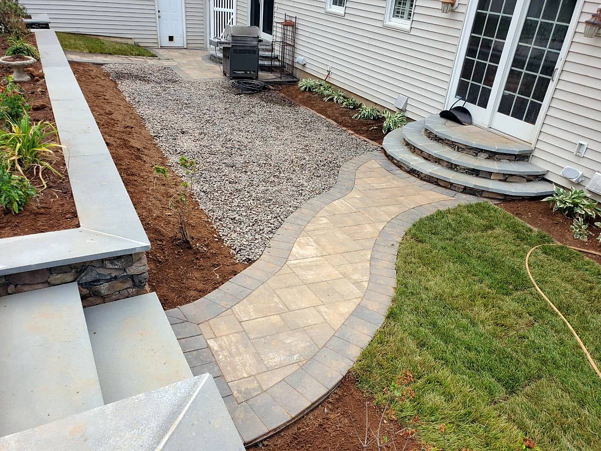 Curved paver walkway with bluestone steps and a stone retaining wall