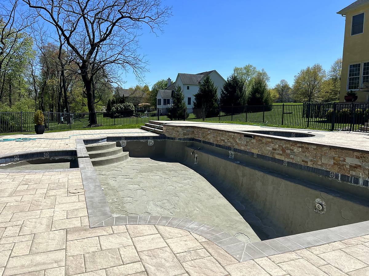 Pool with a stacked-stone spa wall in bond coat before plaster
