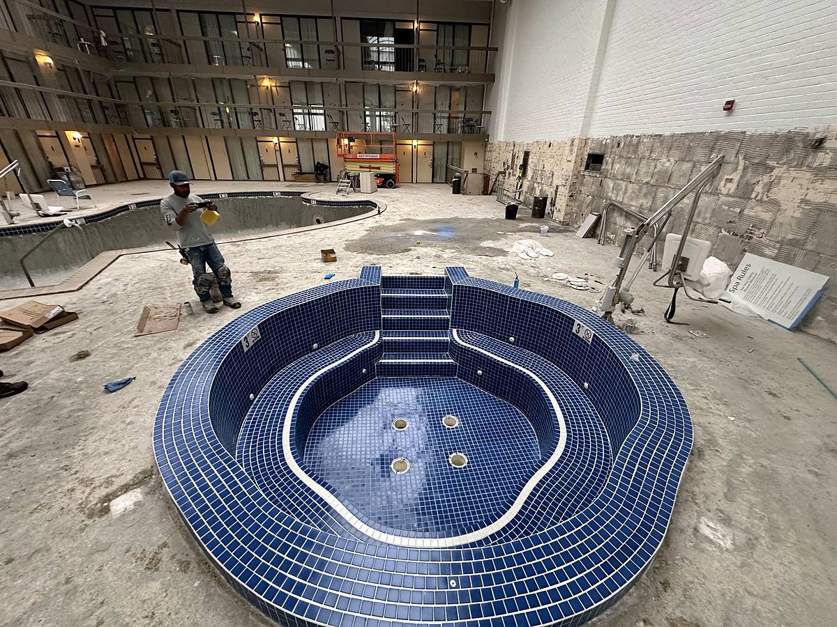 Indoor hotel spa fully retiled in blue glass tile while the pool deck is rebuilt