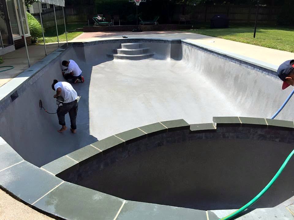 Crew hand-troweling fresh plaster in an empty pool