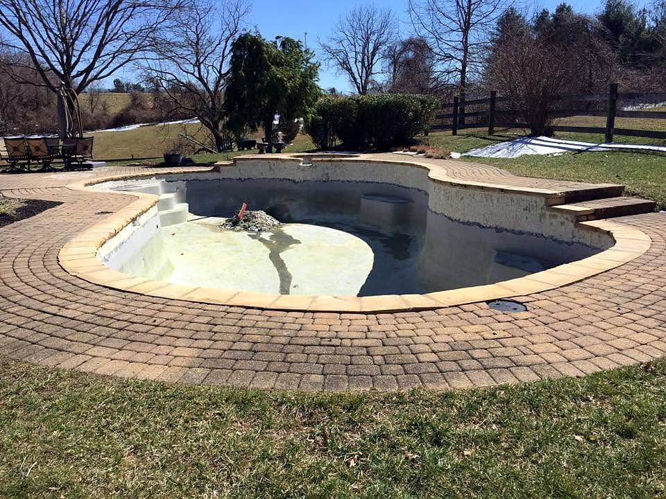 Freeform pool stripped to the shell, with a new paver deck, awaiting plaster